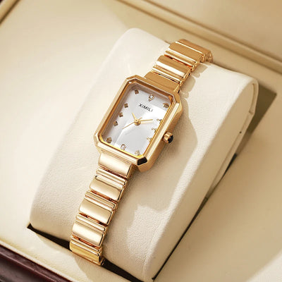 Gold wristwatch with a white face on a beige cushion in a box